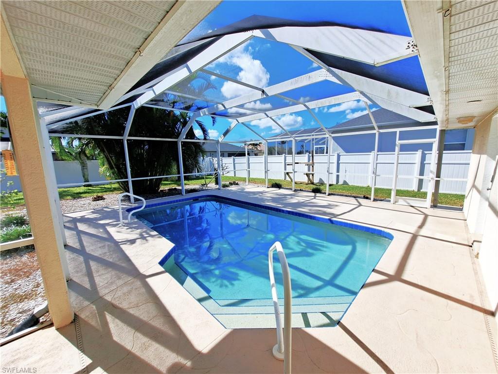 View of pool with glass enclosure and a patio area