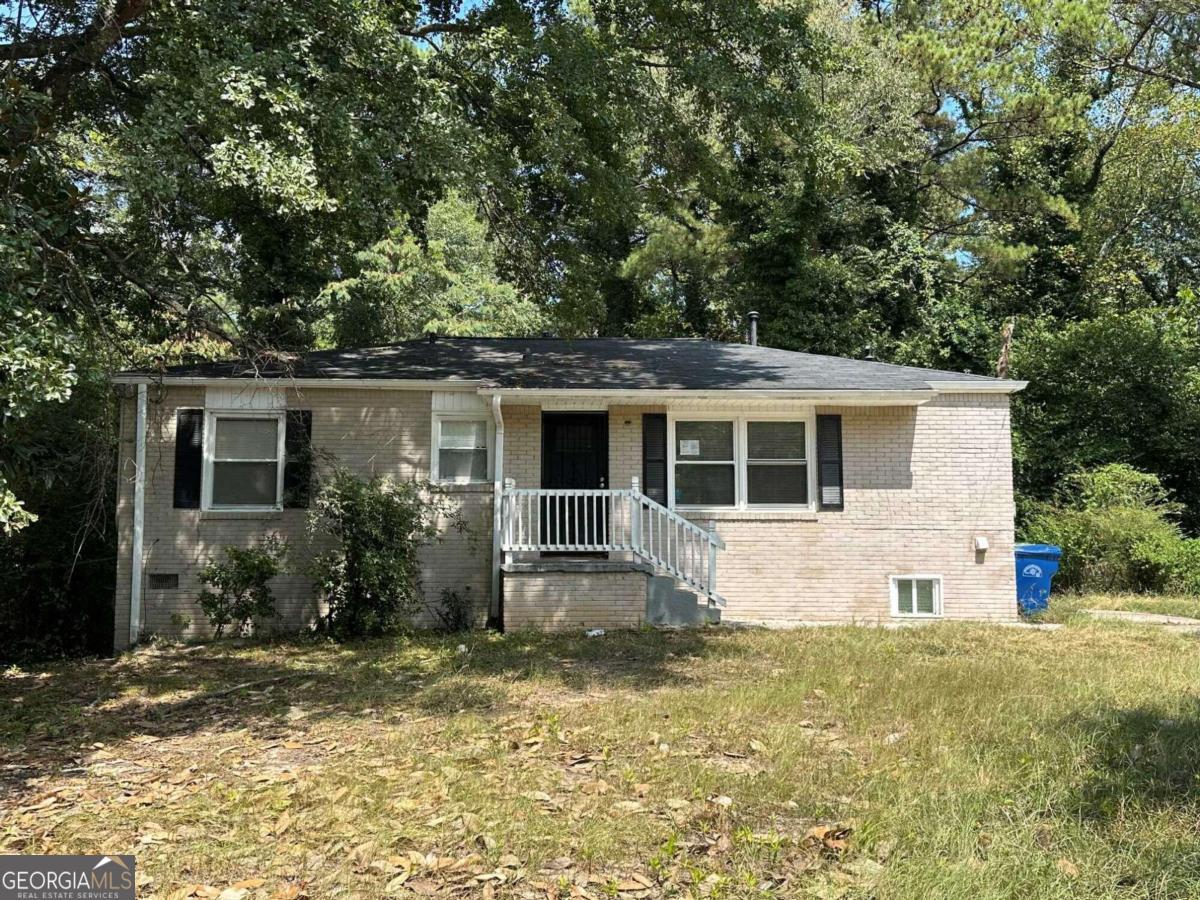 a front view of house with yard and trees in the background