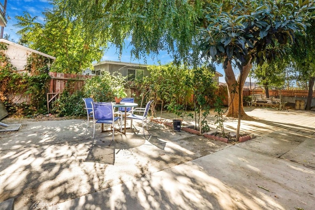 a view of backyard with a table and chairs and a large tree