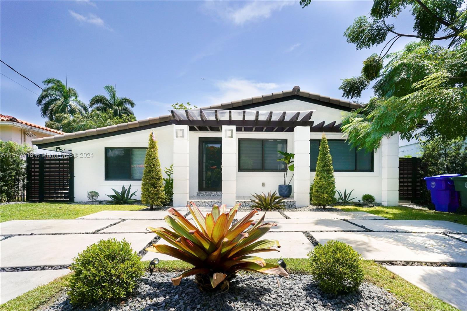 a front view of a house with a garden and potted plants