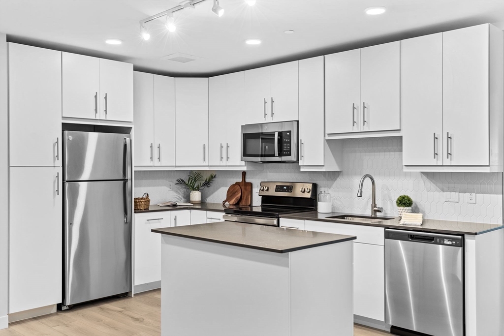 a kitchen with refrigerator a microwave a sink and cabinets