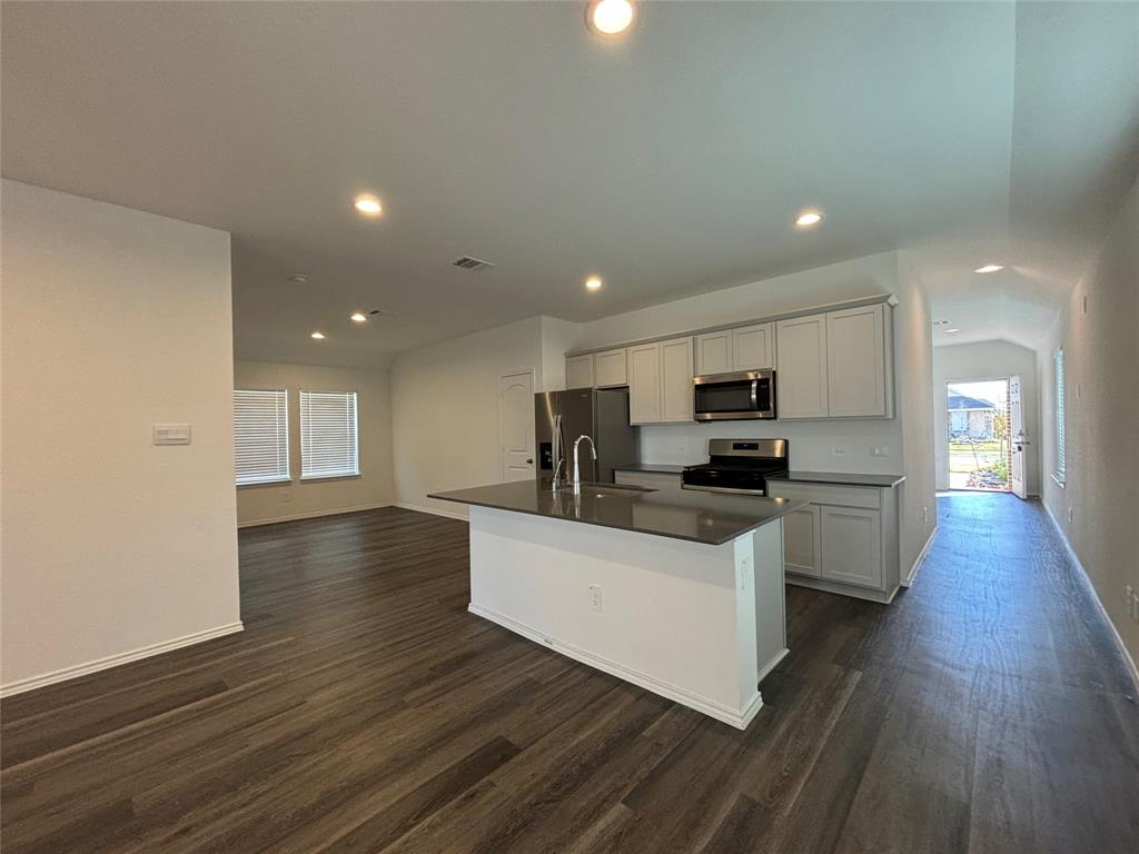 a kitchen with stainless steel appliances kitchen island wooden floors and white cabinets