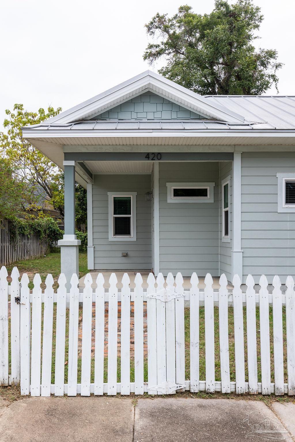 a front view of a house with white fence