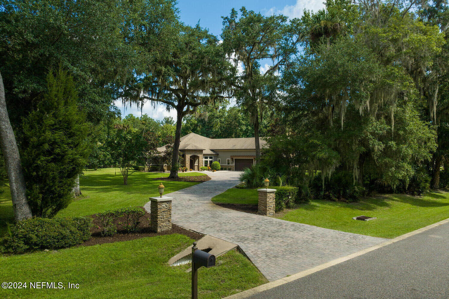 a view of a house with a big yard potted plants and large tree