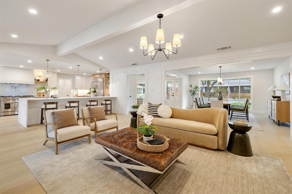 a living room with furniture kitchen view and a chandelier