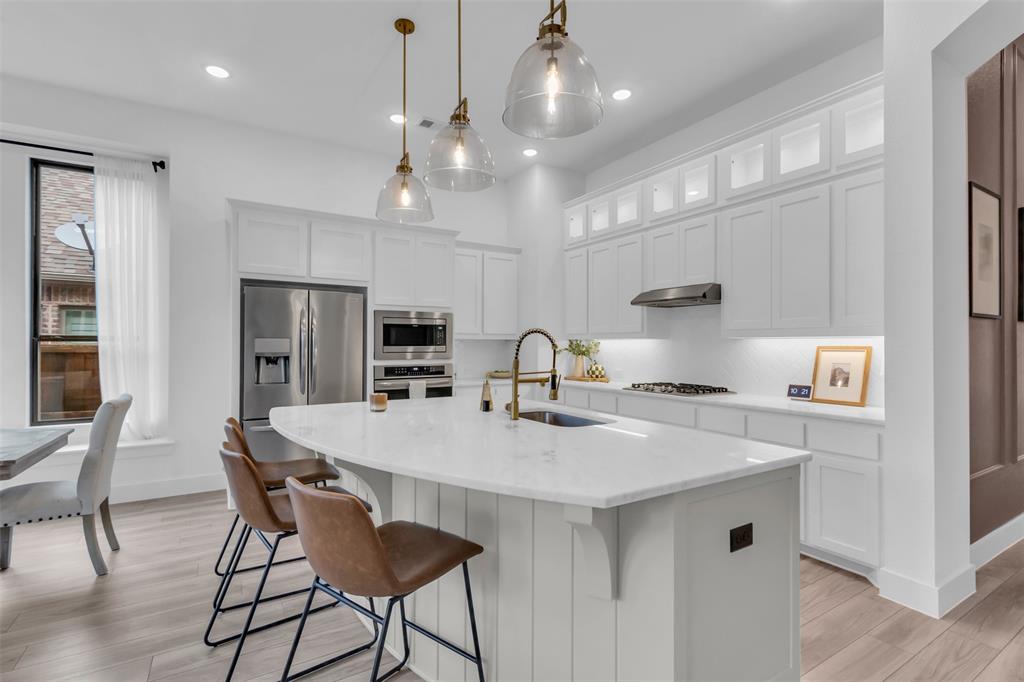 a kitchen with stainless steel appliances a kitchen island a stove a table and chairs in it