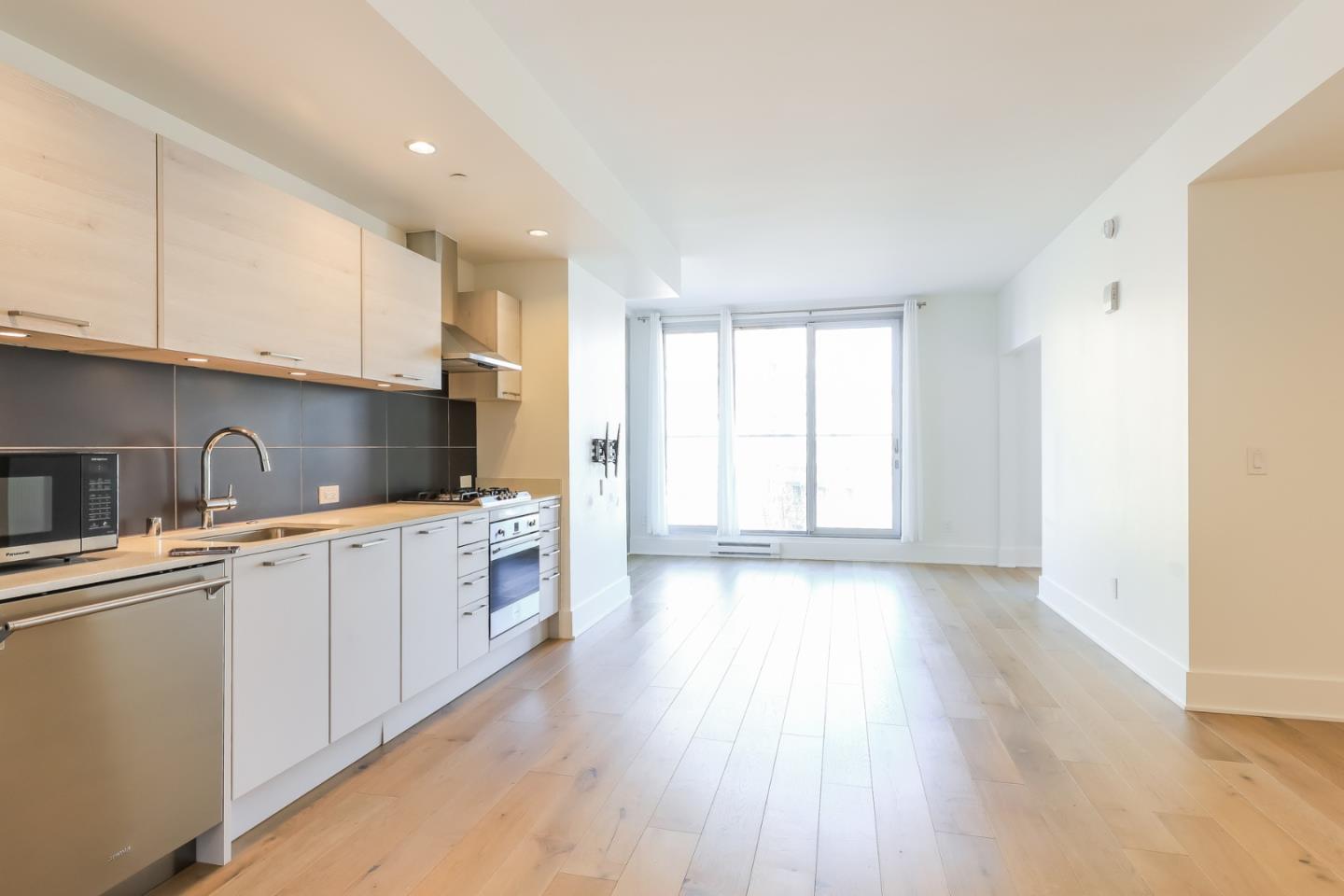 a kitchen with stainless steel appliances granite countertop a stove a sink and white cabinets with wooden floor