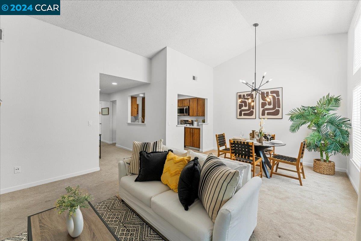 a living room with furniture kitchen view and a potted plants