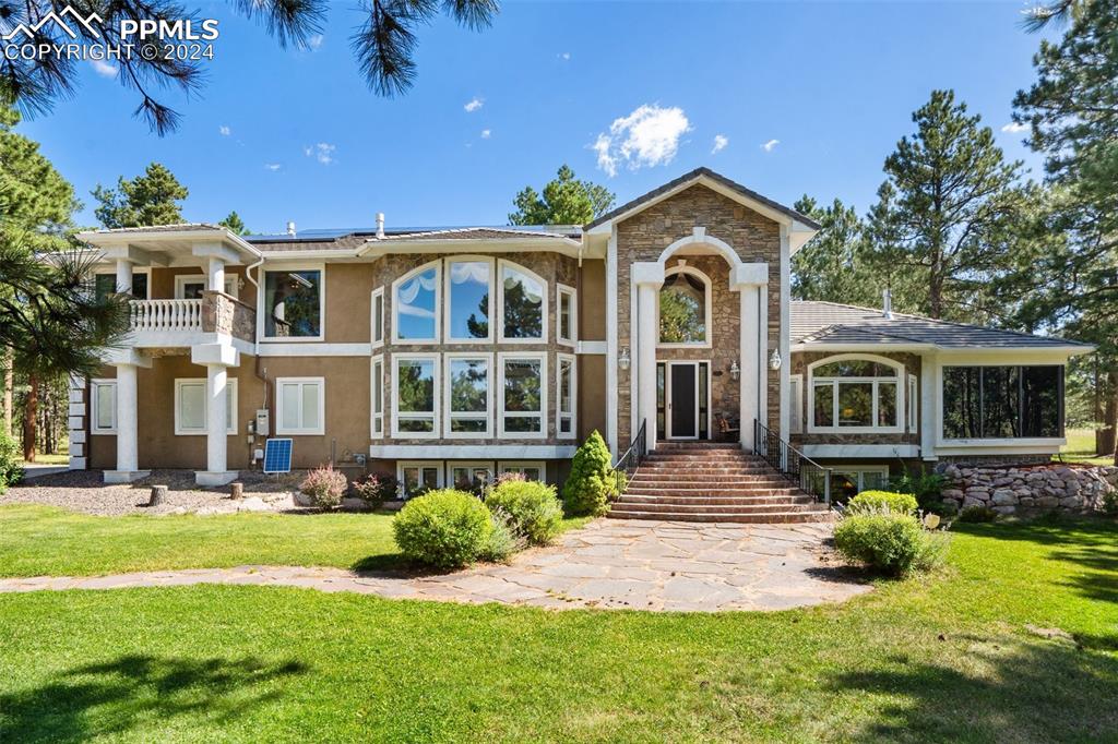 Back of property featuring a balcony and a yard