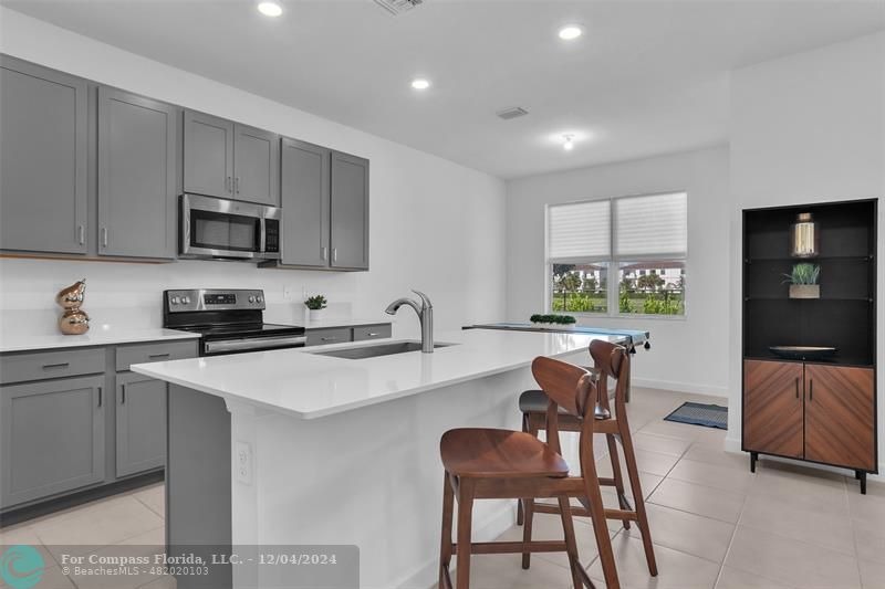 a kitchen with stainless steel appliances granite countertop a stove a sink a microwave a dining table and chairs