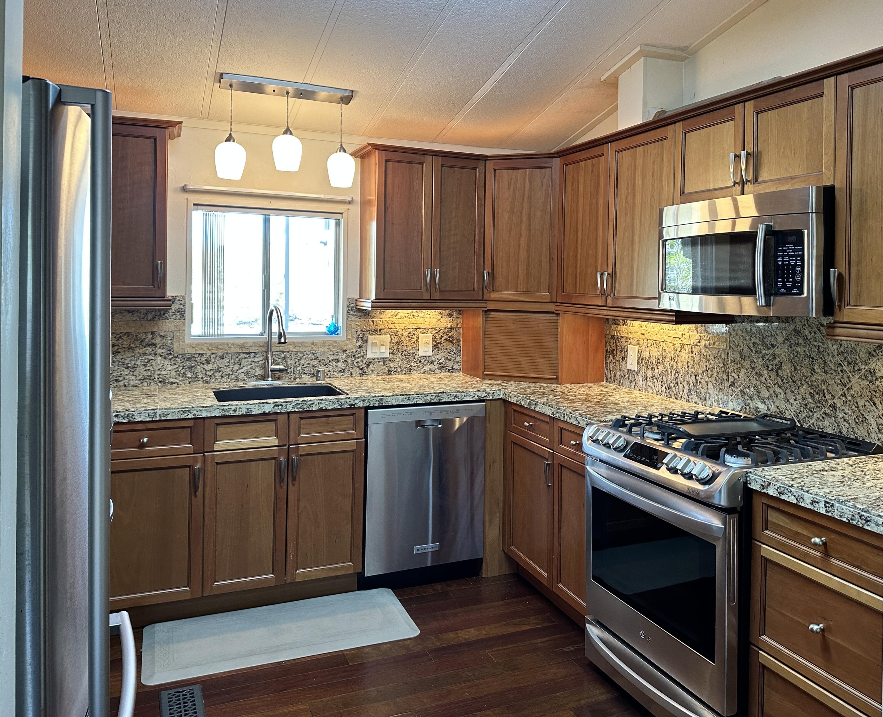 a kitchen with stainless steel appliances granite countertop a stove a microwave and a sink