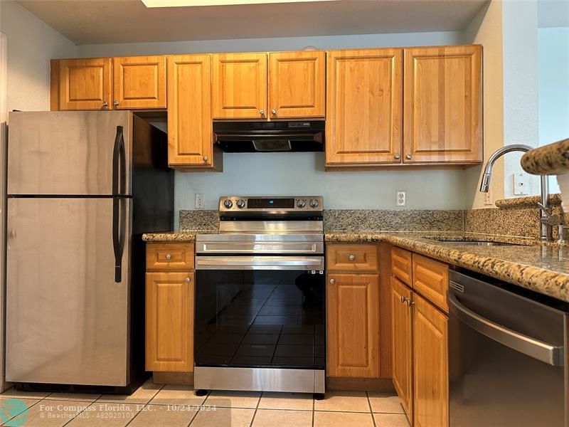 a kitchen with granite countertop a refrigerator stove and cabinets