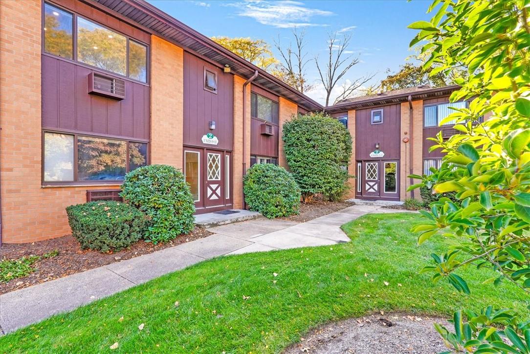 a view of a brick house with a yard and plants