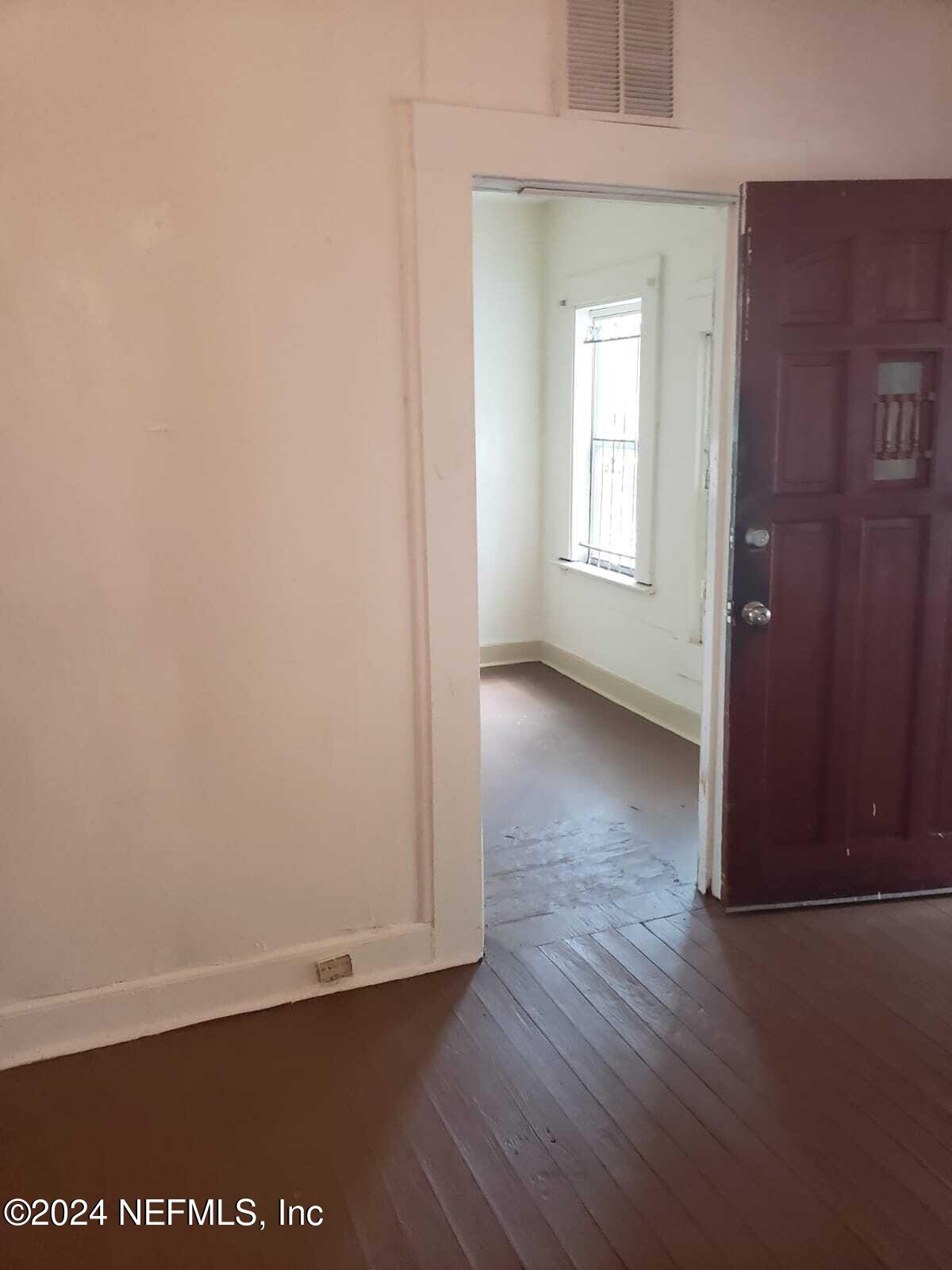 an empty room with wooden floor and windows