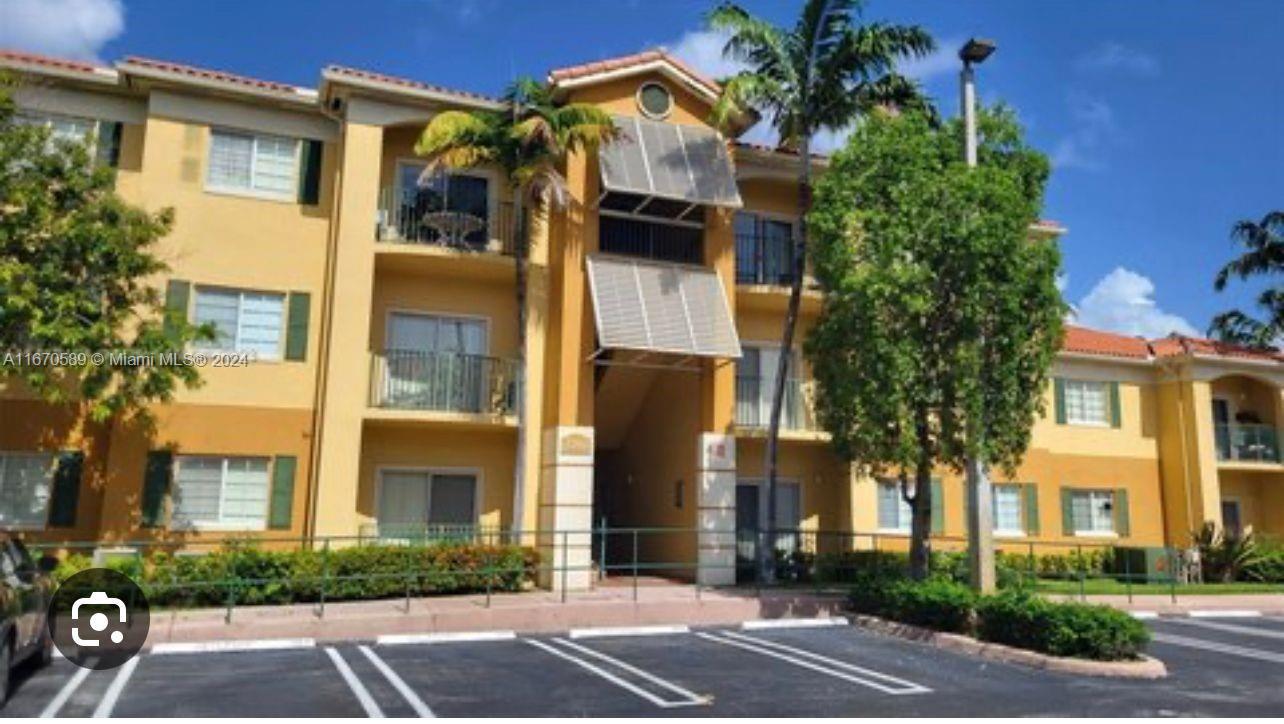 a view of a white building among the street with palm trees