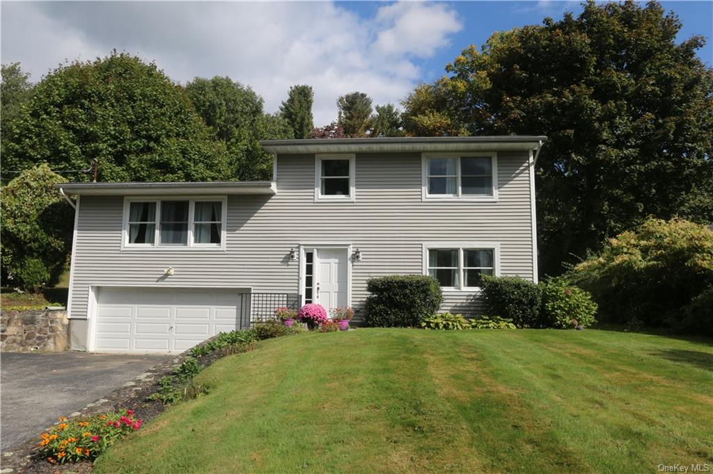 View of front facade featuring a front yard and a garage