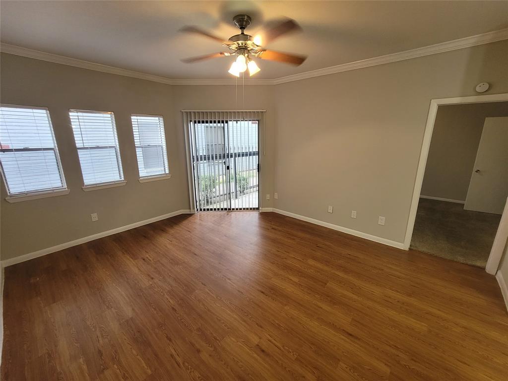 a view of an empty room with a window and wooden floor