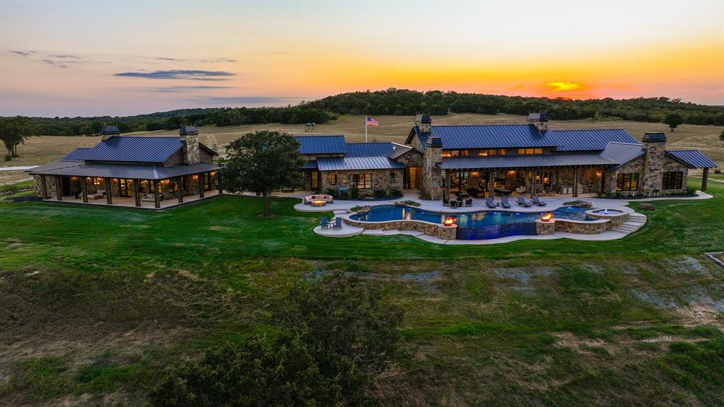 a view of a big house with a big yard and large trees