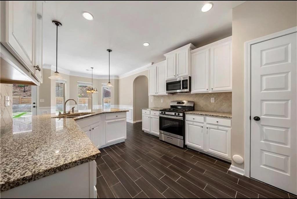 a large kitchen with granite countertop a sink a stove and cabinets