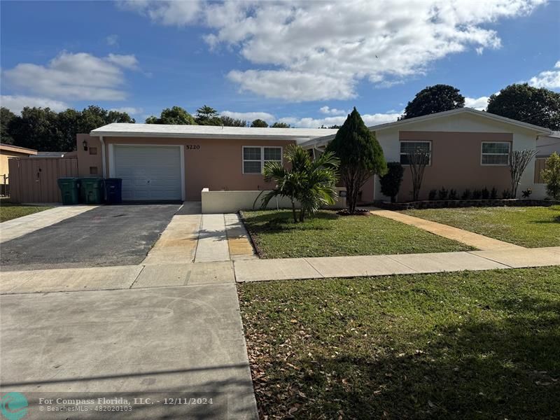 front view of house with a yard and trees in the background