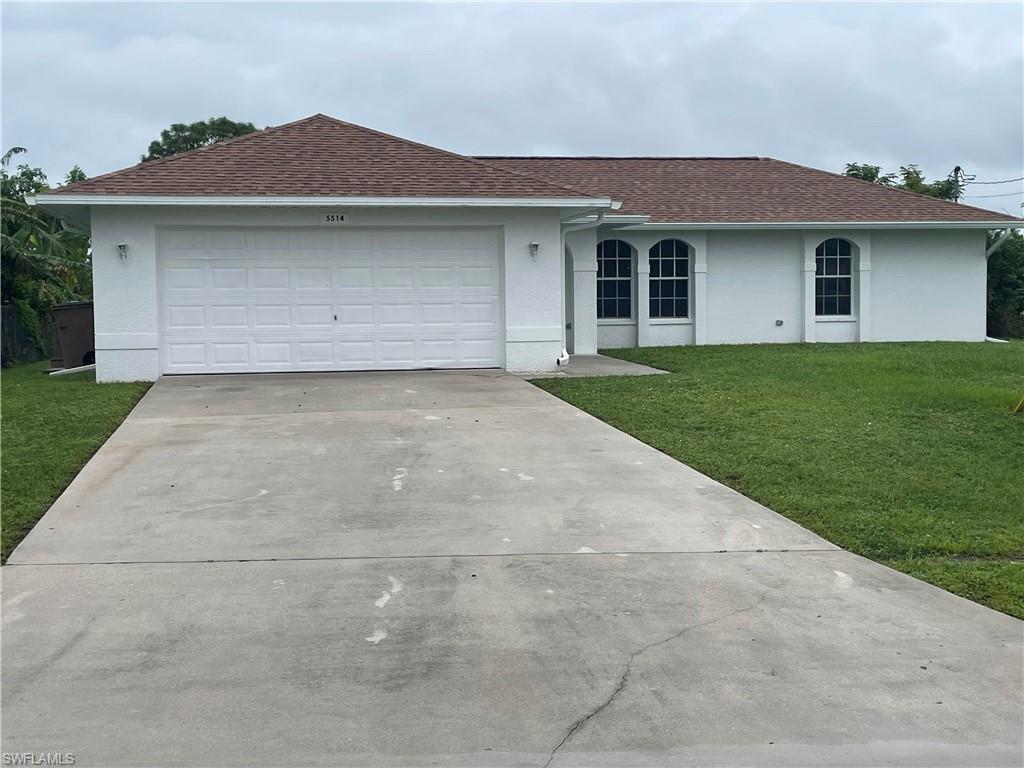 Single story home featuring a garage and a front lawn