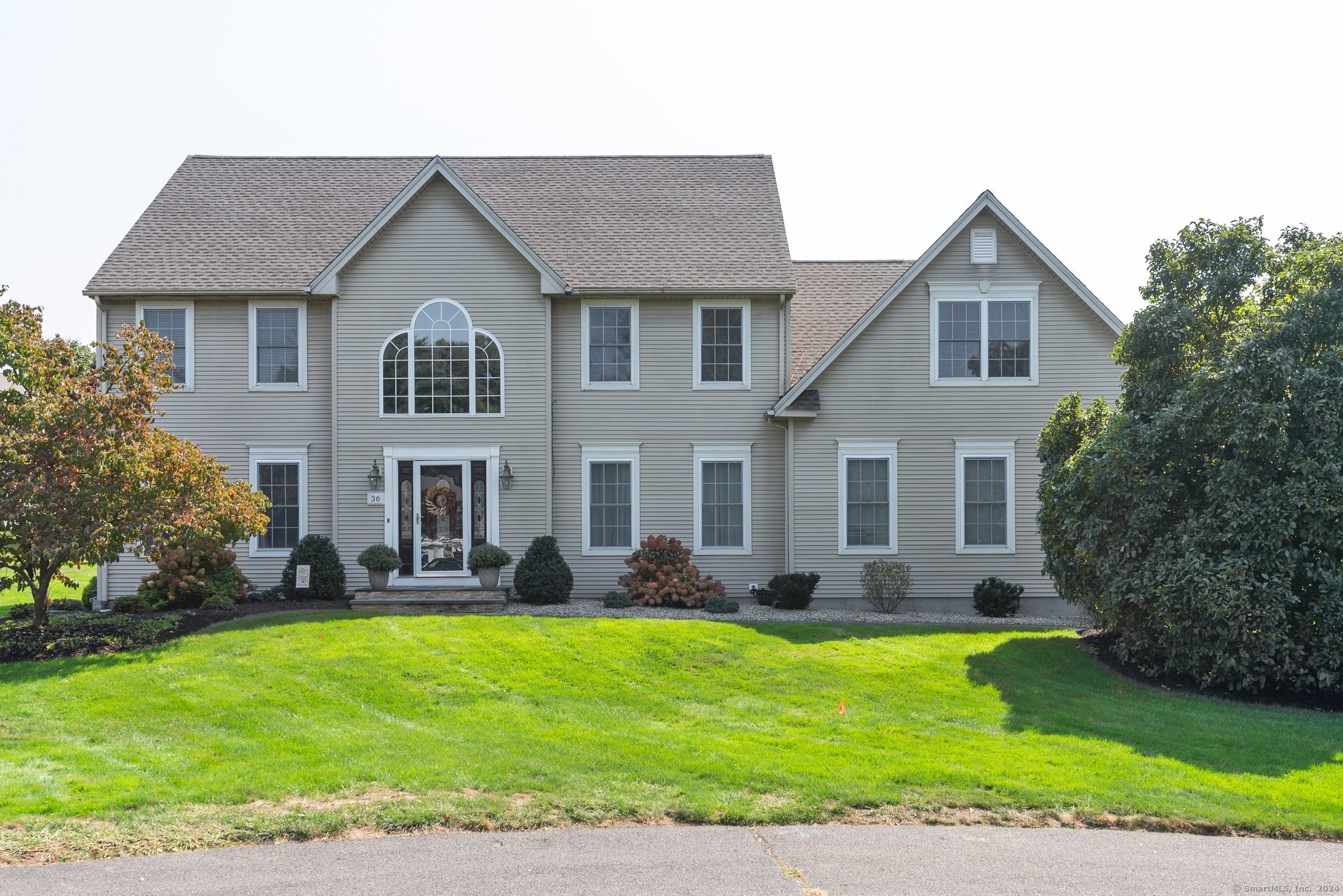 a front view of a house with a yard and potted plants