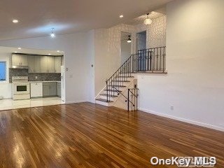 an empty room with wooden floor and kitchen view