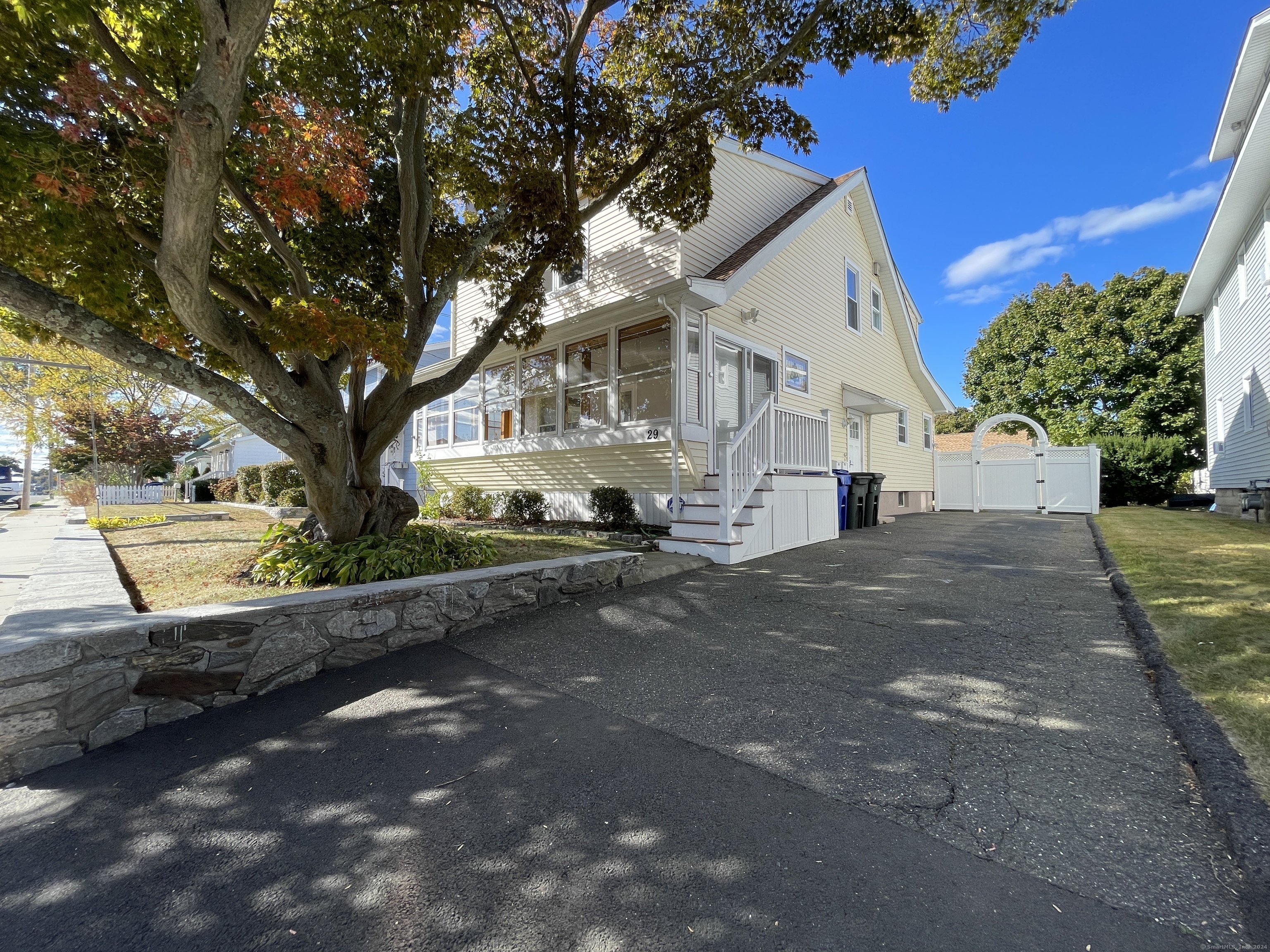 a view of a white house next to a road and yard