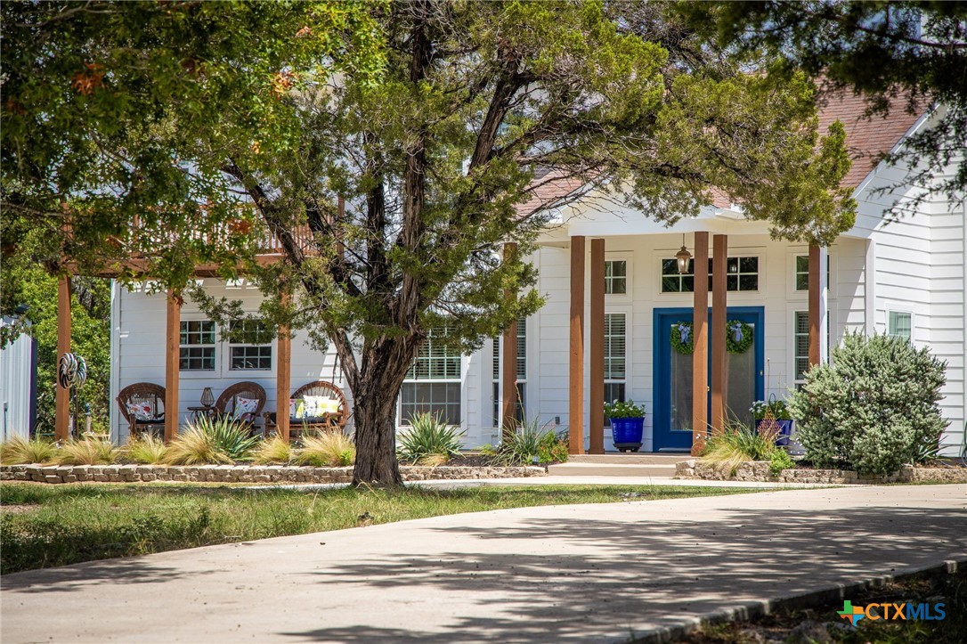 a front view of a house with garden and trees