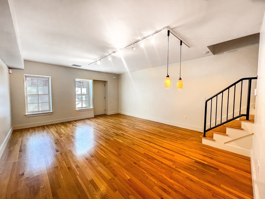 a view of an empty room with window and wooden floor