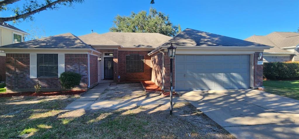 This is a single-story brick home featuring a two-car garage, neat landscaping, and a welcoming entrance. The property boasts a well-maintained appearance in a pleasant neighborhood setting.