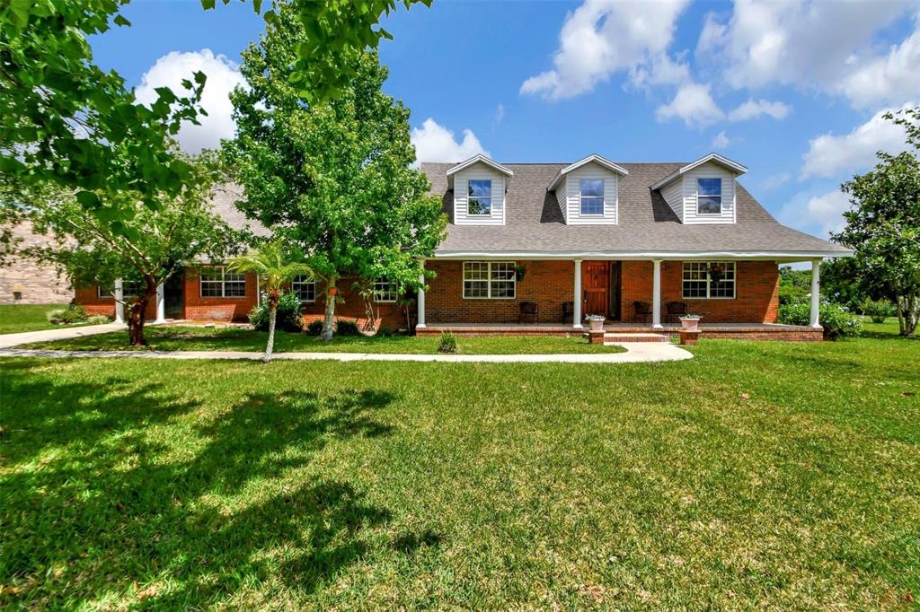 a view of a big house with a big yard and large trees