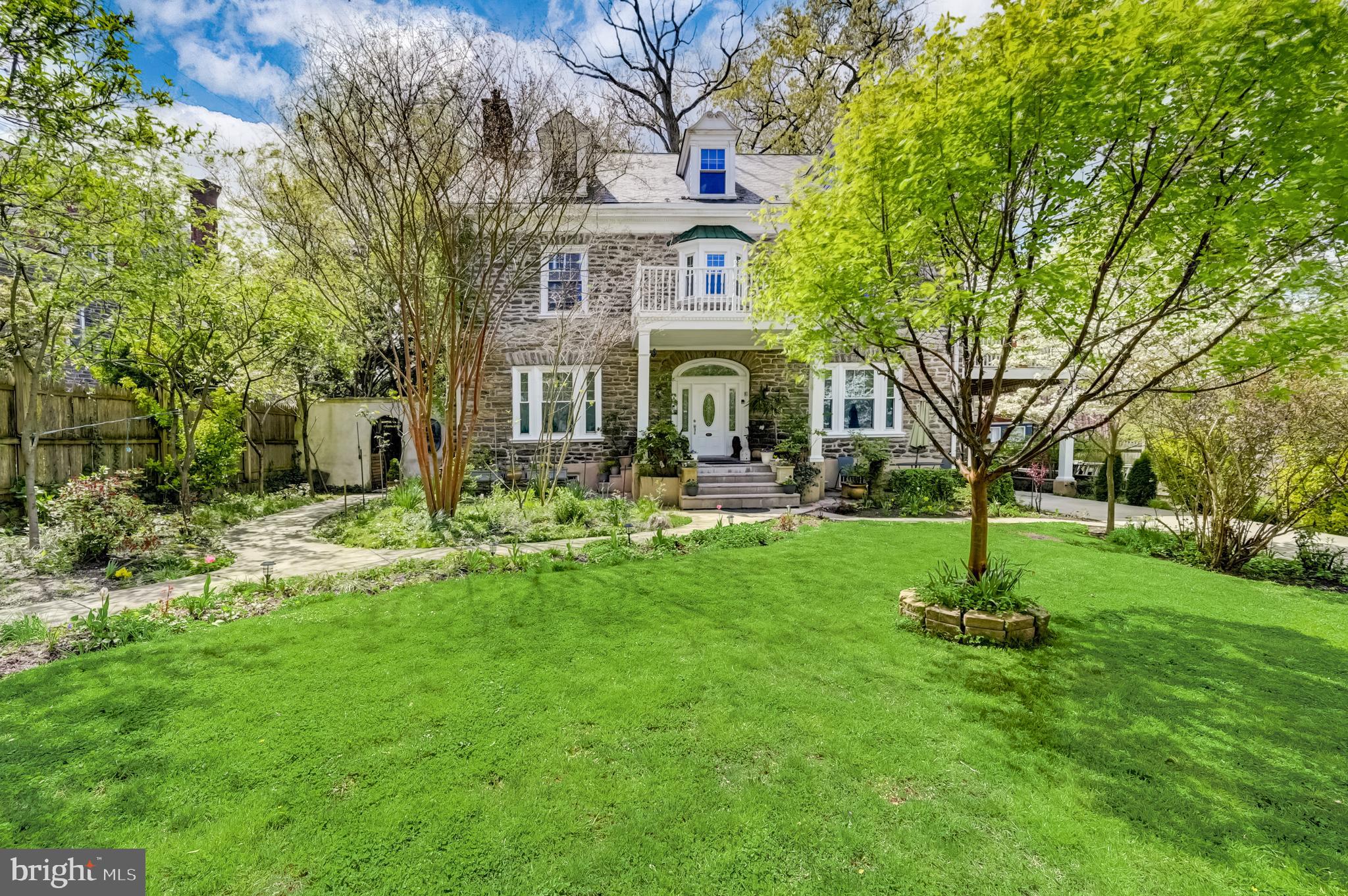 a front view of a house with garden and trees