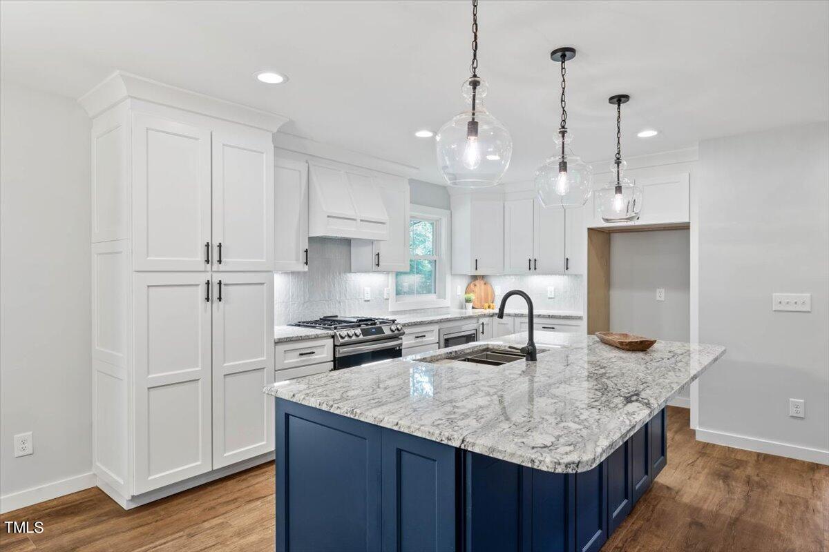 a kitchen with kitchen island granite countertop a sink a counter space appliances and cabinets