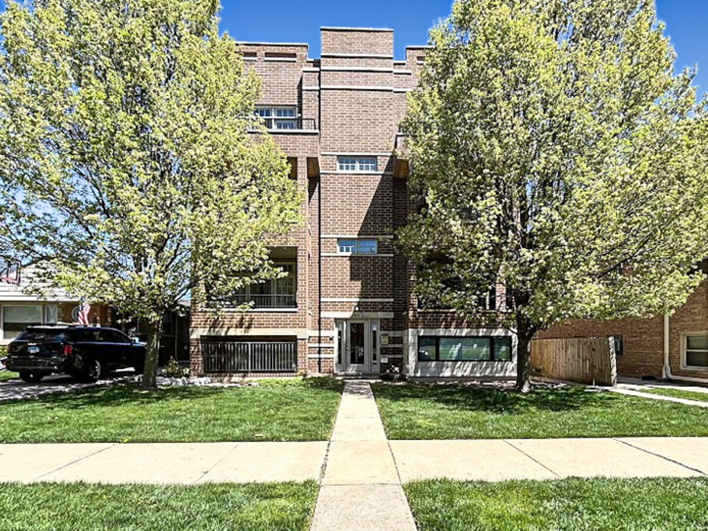 a front view of a house with a garden and trees