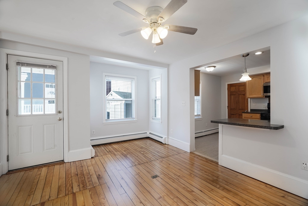 a view of an empty room with window and wooden floor