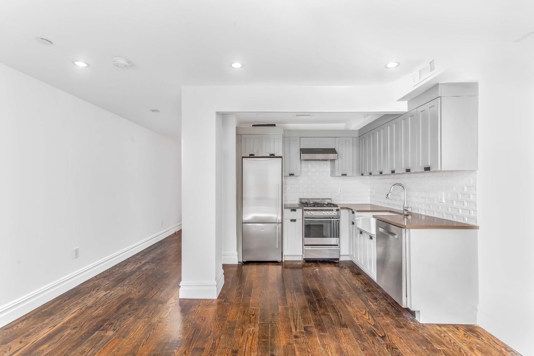 a kitchen with cabinets wooden floor and stainless steel appliances