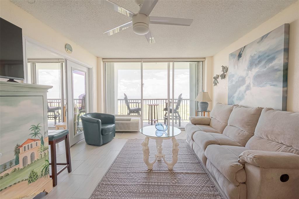 a living room with furniture large windows and wooden floor