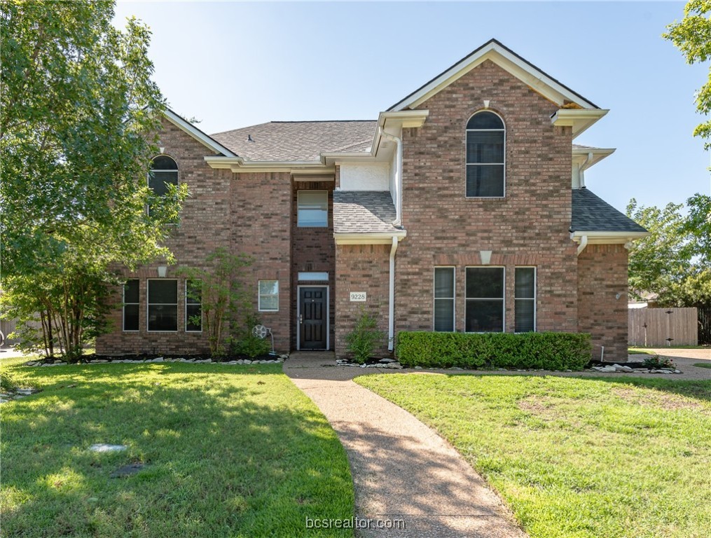 a front view of brick house with yard and trees