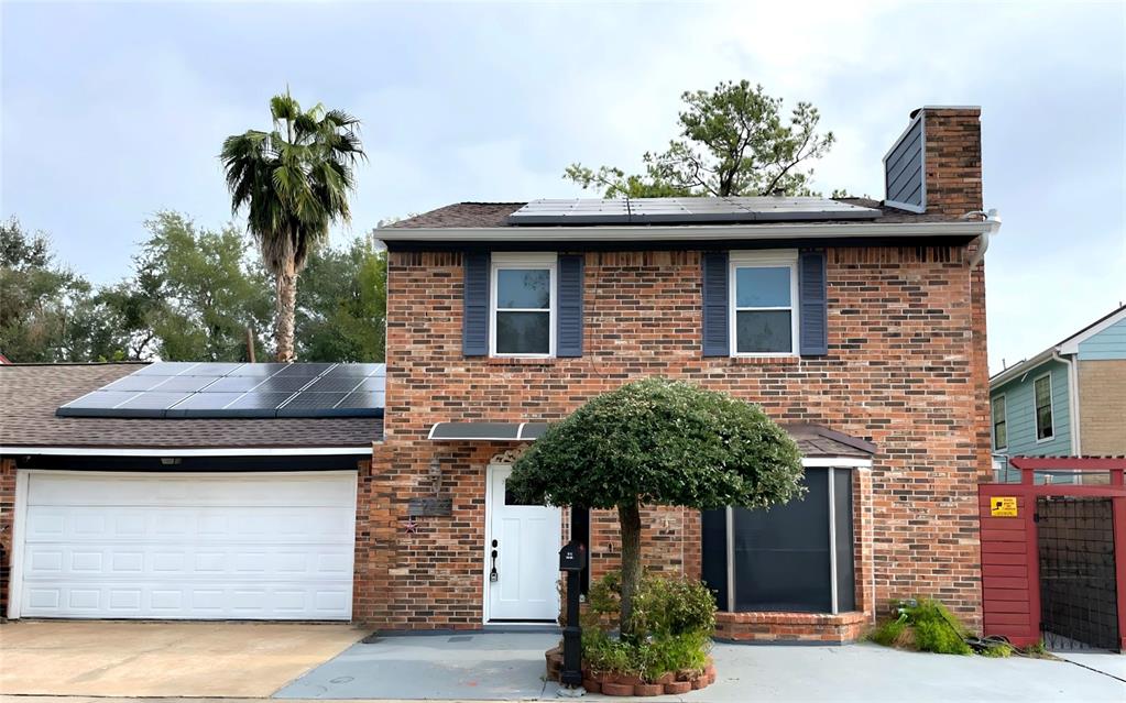 View of front of property with solar panels and a garage.