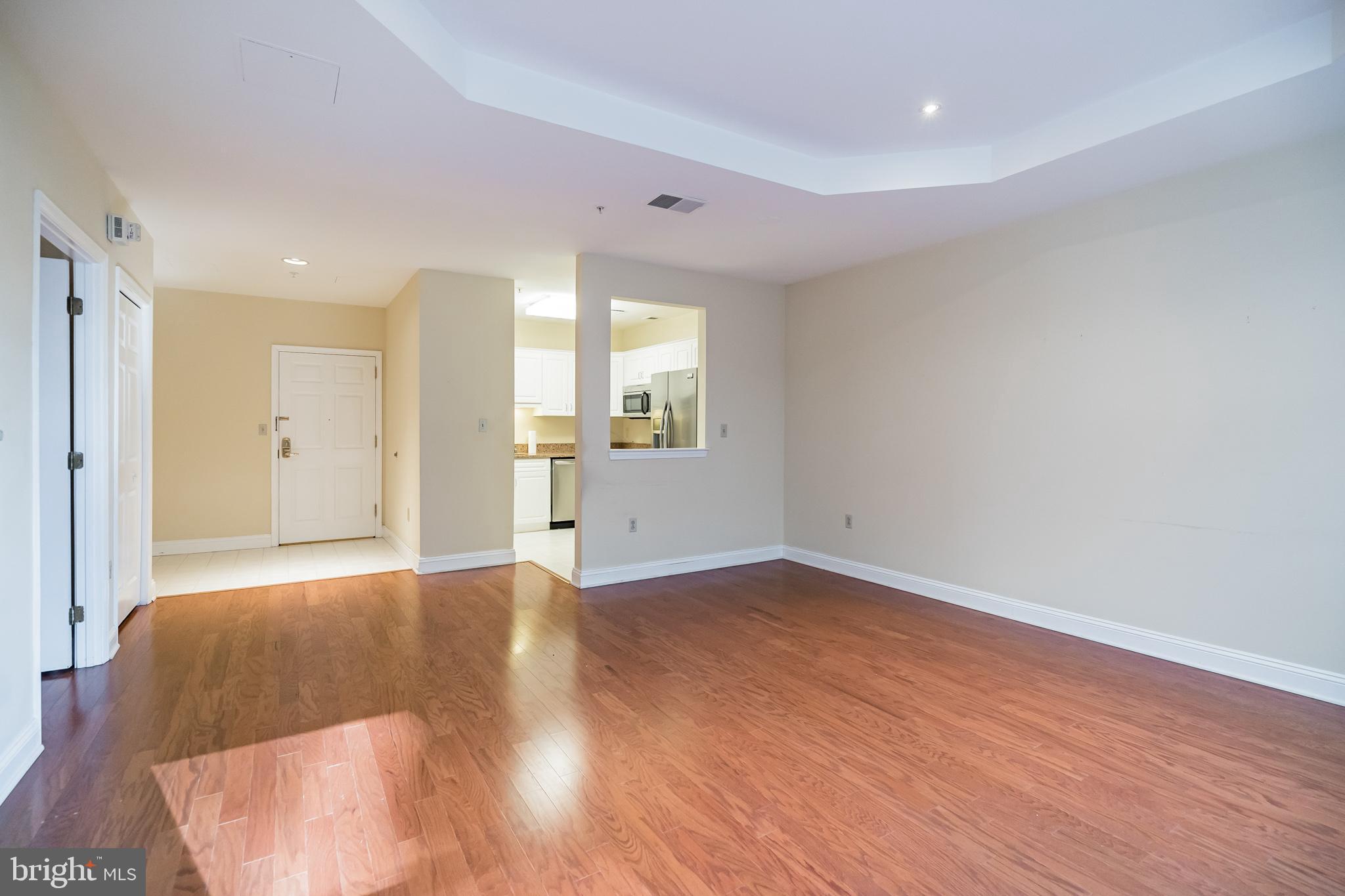 a view of an empty room with window and wooden floor