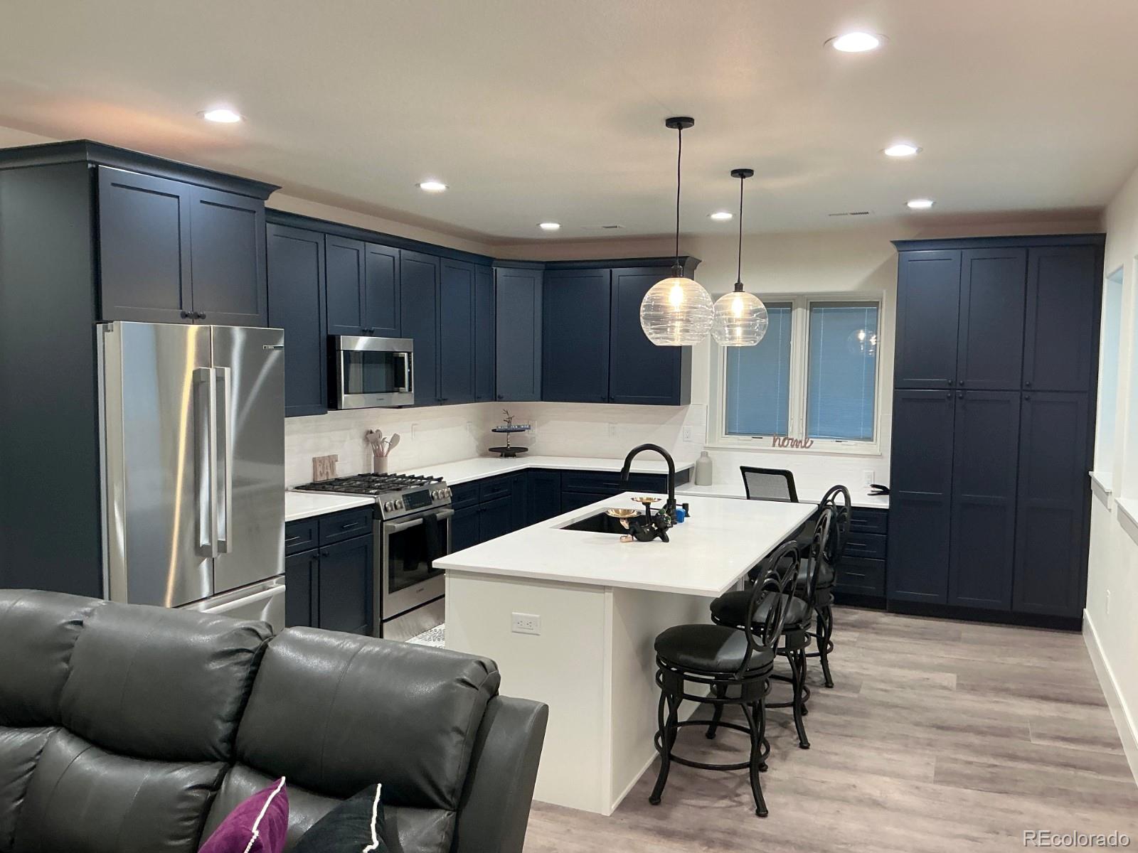 a kitchen with stainless steel appliances kitchen island granite countertop a refrigerator a stove a sink dishwasher a dining table and chairs with wooden floor