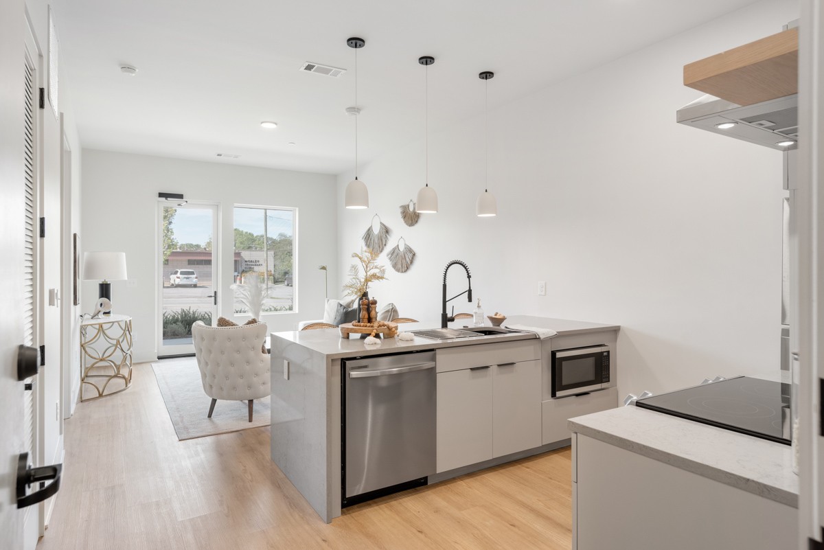 a kitchen with a sink dishwasher stove and white cabinets with wooden floor