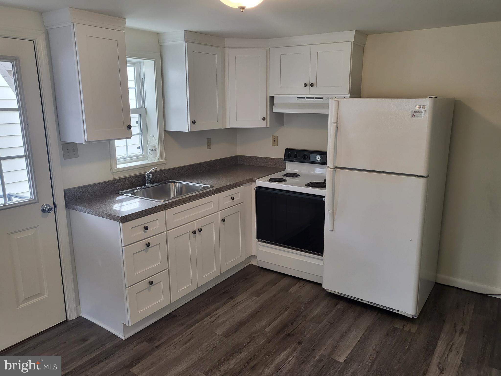 a kitchen with cabinets appliances wooden floor and a window