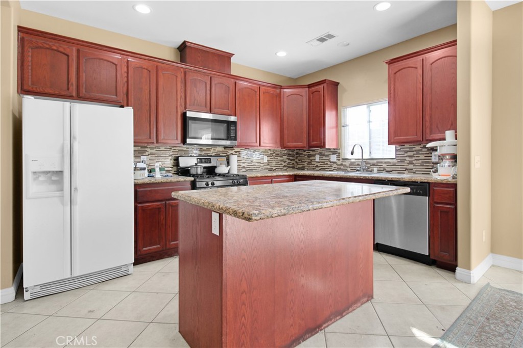 a kitchen with stainless steel appliances granite countertop a stove a refrigerator a sink and dishwasher