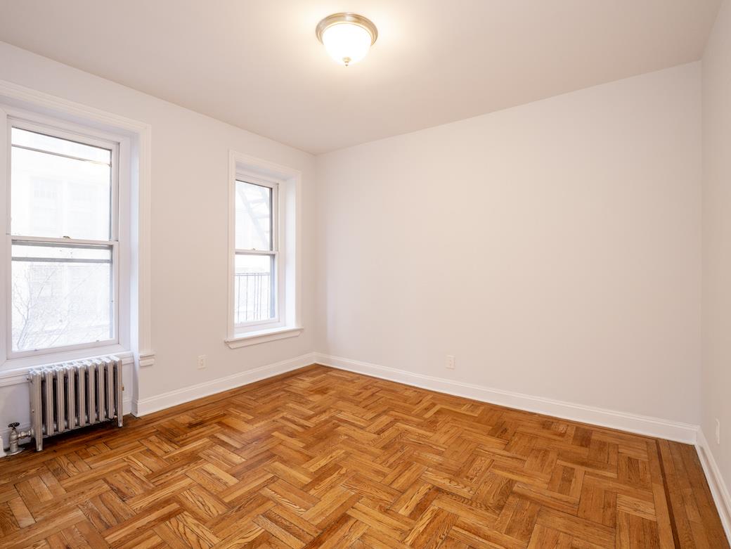 a view of a bedroom with wooden floor and a window