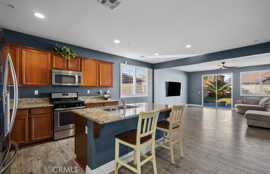 a kitchen with stainless steel appliances granite countertop wooden floor a stove top oven a sink dishwasher a dining table and chairs with wooden floor
