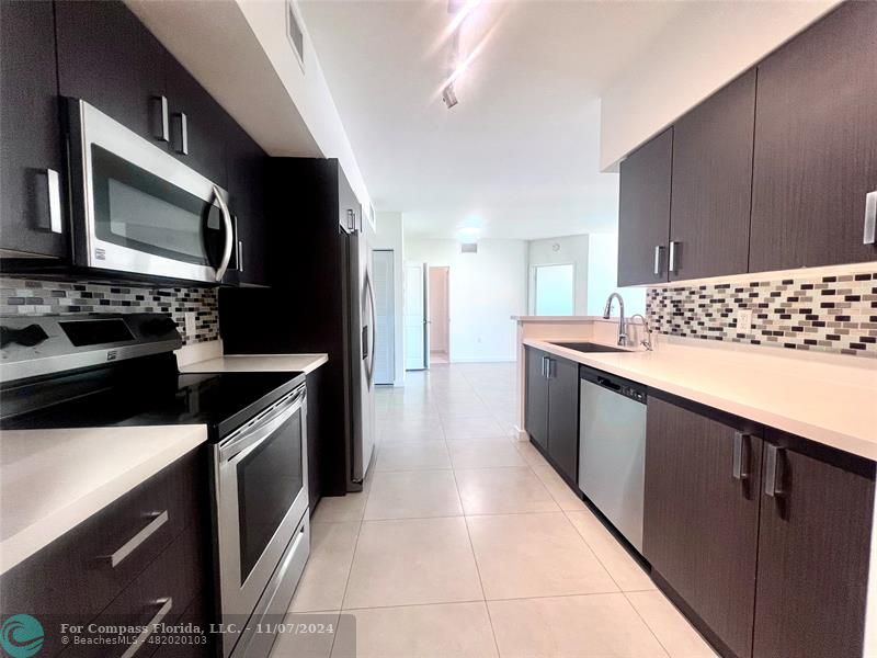 a kitchen with stainless steel appliances granite countertop a stove a sink and a microwave