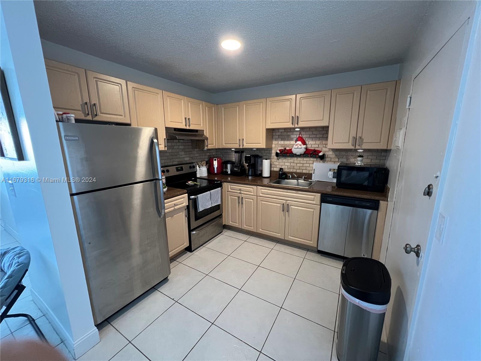 a kitchen with granite countertop a refrigerator sink and cabinets