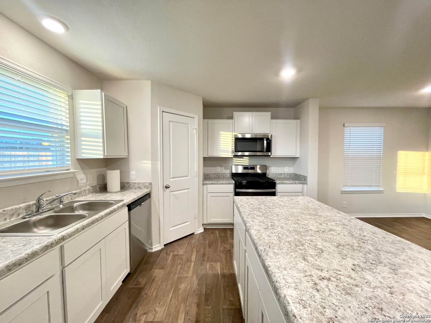 a large kitchen with a stove top oven a sink dishwasher and wooden floor